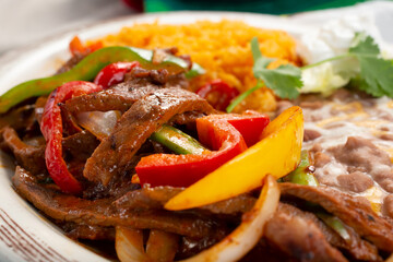 A closeup view of a plate of steak fajitas, in a restaurant or kitchen setting.