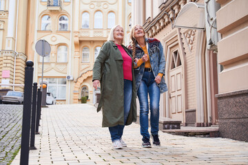Woman walking arm in arm with her dear senior mother