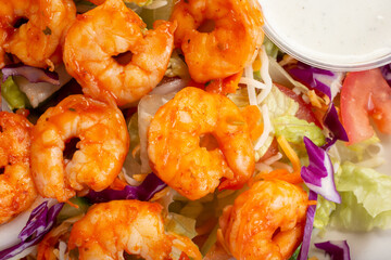 A closeup top down view of a shrimp salad, in a restaurant or kitchen setting.