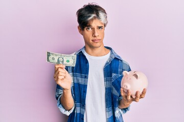 Young hispanic man holding dollar and piggy bank skeptic and nervous, frowning upset because of problem. negative person.