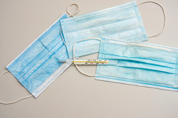 The thermometer lies on three masks on the table, top view.