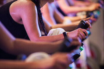 Sweaty torso of caucasian woman on a stationary bike in a line of other riders at a group spin class - obrazy, fototapety, plakaty
