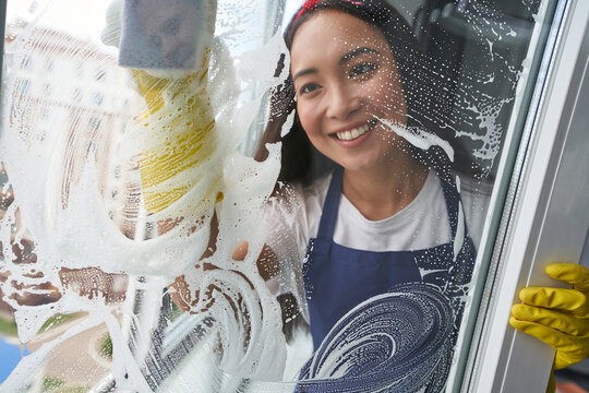 Extreme Clean. Cheerful Young Woman Smiling While Cleaning The Window, Glass Surface Using Sponge