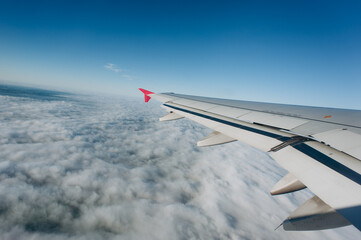 Wing of a jet on the blue sky background. Concept of travel and air transportation industry.