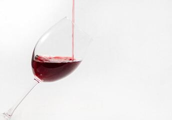 Red wine poured in a glass isolated on white.