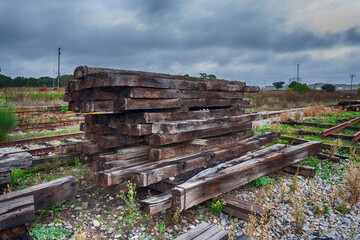 Fototapeta na wymiar A pile of old timbers for the construction and repair of abandoned train tracks in a railway station