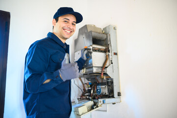 Fototapeta na wymiar Smiling technician repairing an hot-water heater and showing thumbs up