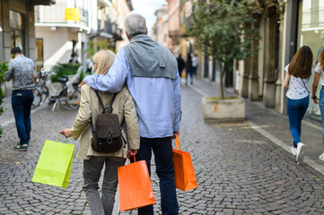 Senior couple shopping outdoor at coronavirus times, wearing masks