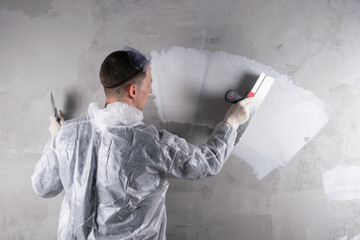 master plasterer makes a white strip with a trowel on a concrete wall, place for your lettering