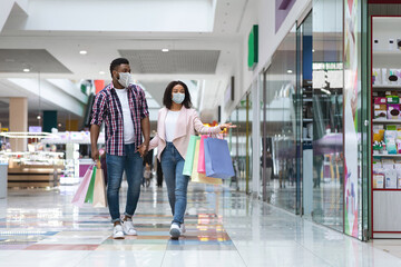 Young black couple wearing protective medical face mask walking in shopping mall