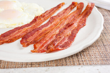 A view of several strips of bacon on a breakfast plate.
