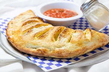 A view of a plate of calzone, in a restaurant or kitchen setting.