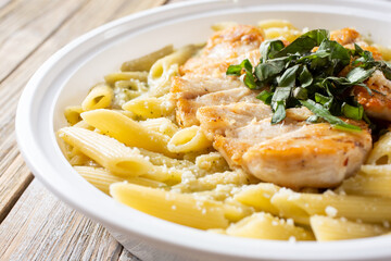 A closeup view of a bowl of chicken penne Alfredo.