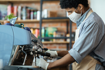Professional barista works with equipment in cafe during social distancing