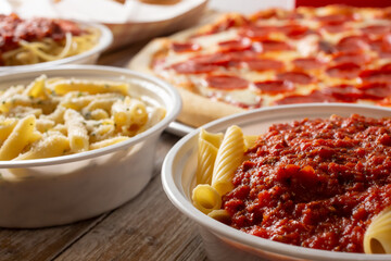 A view of several popular Italian entrees, featuring penne marinara and a pepperoni pizza.