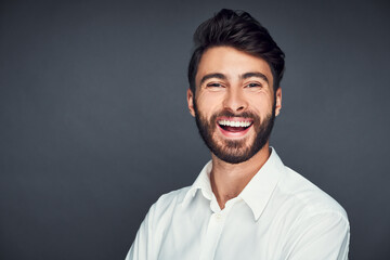 Portrait of successful young man smiling isolated on dark background