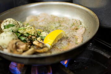A closeup view of a stove top pan cooking a shrimp entree.