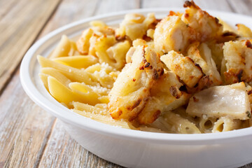 A closeup view of a bowl of chicken penne Alfredo.
