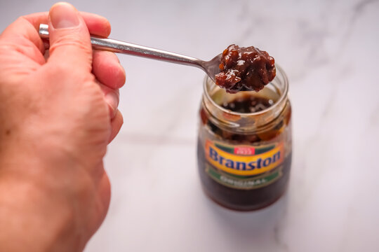Norwich, Norfolk, UK &ndash; September 22 2020. An illustrative photo of an unidentifiable human hand, in soft focus, holding a spoon of Branstons original pickle