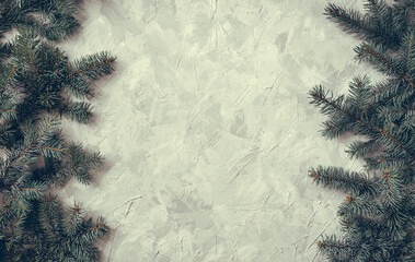 Christmas gray grunge background, fir twigs, top view. Winter holidays, New Year decoration, pine tree branches vertical both sides on light concrete, rough cement texture, flat lay, copy space.
