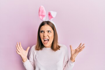 Young caucasian woman wearing cute easter bunny ears showing and pointing up with fingers number three while smiling confident and happy.