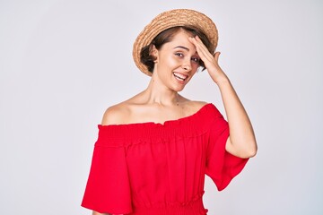 Young hispanic woman wearing summer hat surprised with hand on head for mistake, remember error....
