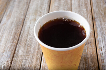 A view of a general cup of black coffee, on a wooden table surface.