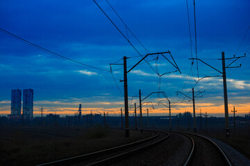 Fototapeta na wymiar Railway line near the industrial zone at sunset or dawn