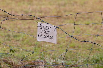 Keep out, private sign fixed to barbed wire fence