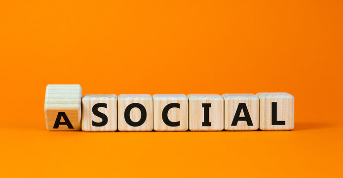 Social or asocial. Fliped wooden cubes and changed the word 'asocial' to 'social' or vice versa. Beautiful orange background, copy space. Business and asocial or social concept.