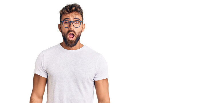 Young hispanic man wearing casual clothes and glasses afraid and shocked with surprise and amazed expression, fear and excited face.