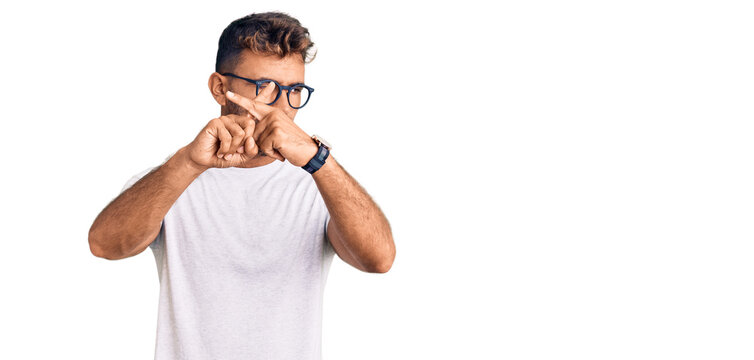 Young hispanic man wearing casual clothes and glasses rejection expression crossing fingers doing negative sign