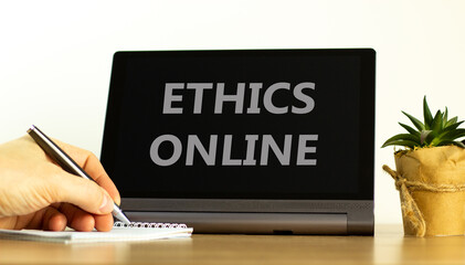 Ethics online. Tablet with words ethics online. Male hand with pen, house plant. Copy space....