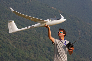 Man in sunglasses is playing with a ero plane glider discus 2c model with remote control in the top...
