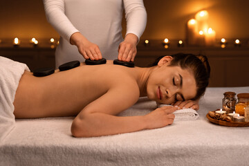 Obraz na płótnie Canvas Relaxed lady receiving hot stone massage at modern spa