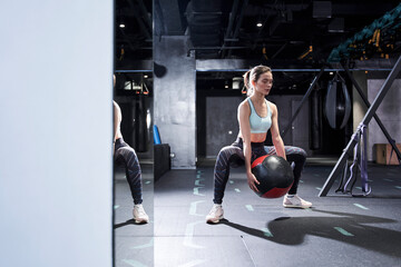 Obraz na płótnie Canvas Woman doing exercise with heavy medicine ball