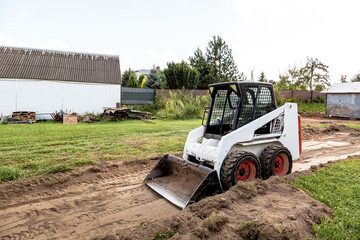 A skid steer loader clears the site for construction. Land work by the territory improvement....