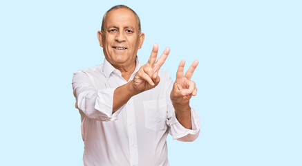 Handsome senior man wearing elegant white shirt smiling looking to the camera showing fingers doing victory sign. number two.