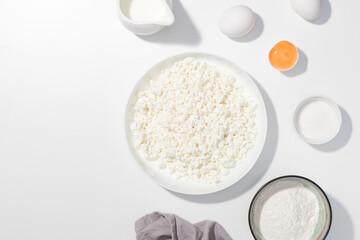 Step-by-step recipe - Cottage cheese, eggs, sugar, cream and yougurt on a white background - Flat lay