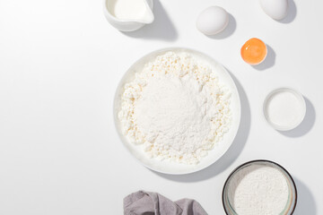 Step-by-step recipe - Cottage cheese, eggs, sugar, cream and yougurt on a white background - Flat lay