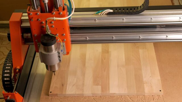 A cnc wood woodworking machine drills a circle in the board. Top View