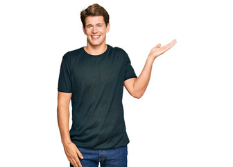 Handsome caucasian man wearing casual clothes smiling cheerful presenting and pointing with palm of hand looking at the camera.