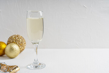 Wineglass full of dry white Prosecco sparkling champagne with golden christmas or new year decoration balls on wooden table against white background. Image with copy space, horizontal