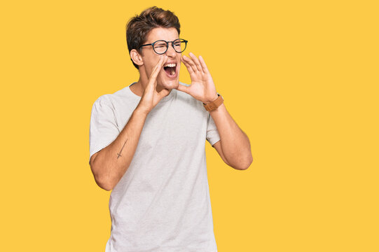 Handsome caucasian man wearing casual clothes and glasses shouting angry out loud with hands over mouth