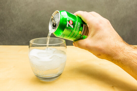 Niedomice, Poland - March 09, 2018: Pouring a carbonated drink 7up from a can into a glass with ice cubes.