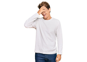 Handsome caucasian man wearing casual white sweater smiling and laughing with hand on face covering eyes for surprise. blind concept.