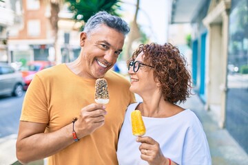 Middle age couple smiling happy eating ice cream at street of city.