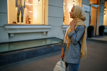 Fototapeta premium Arab girl in hijab looking on showcase in downtown