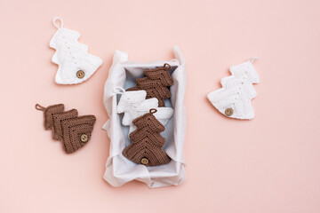 Christmas handmade. Knitted fir-trees in a gift box on a pastel color. Handicraft and leisure