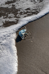 surgical mask abandoned on the beach - pollution from human neglect